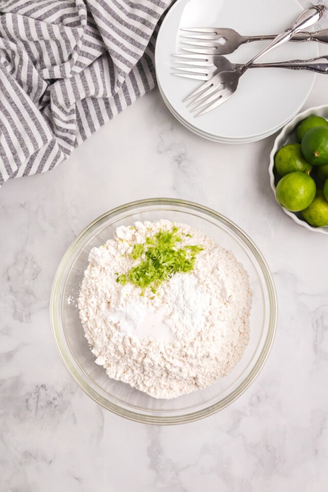 overhead view of flour, baking powder, baking soda, salt, and lime zest in a mixing bowl