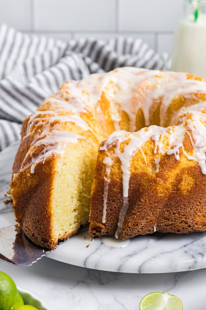 a slice of Key lime Bundt cake on a cake server being removed from the remaining cake