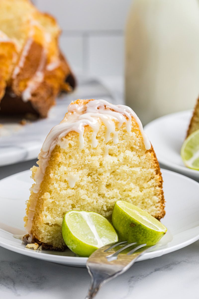 a slice of Key lime Bundt cake on a white plate with two lime wedges