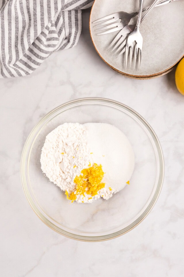 overhead view of flour, sugar, and lemon zest in a mixing bowl