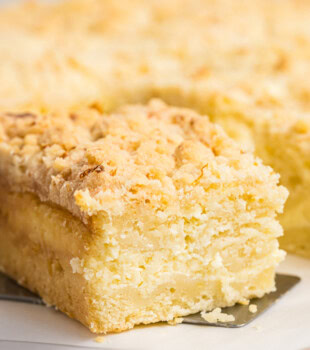 close up view of a slice of lemon cream cheese coffee cake showing layers of lemon cake, sweetened cream cheese, and crumb topping