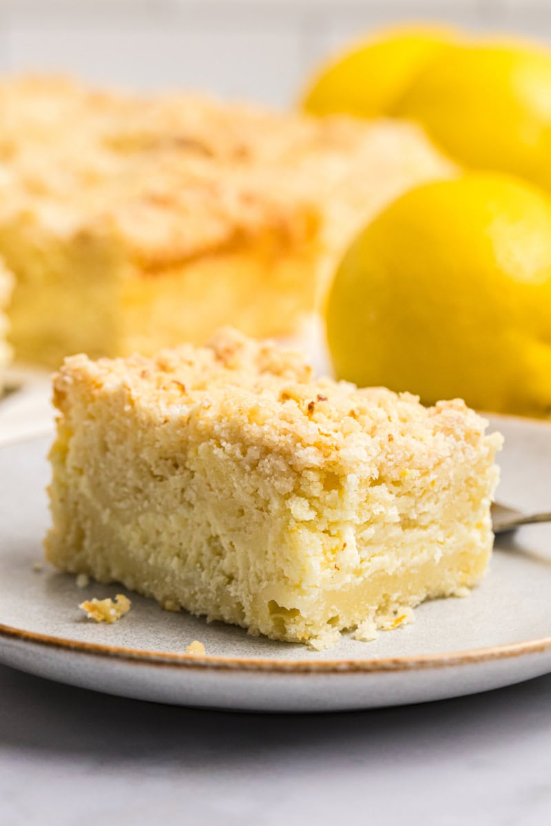 a slice of lemon cream cheese coffee cake featuring layers of lemony cake, sweet cream cheese, and a crumb topping