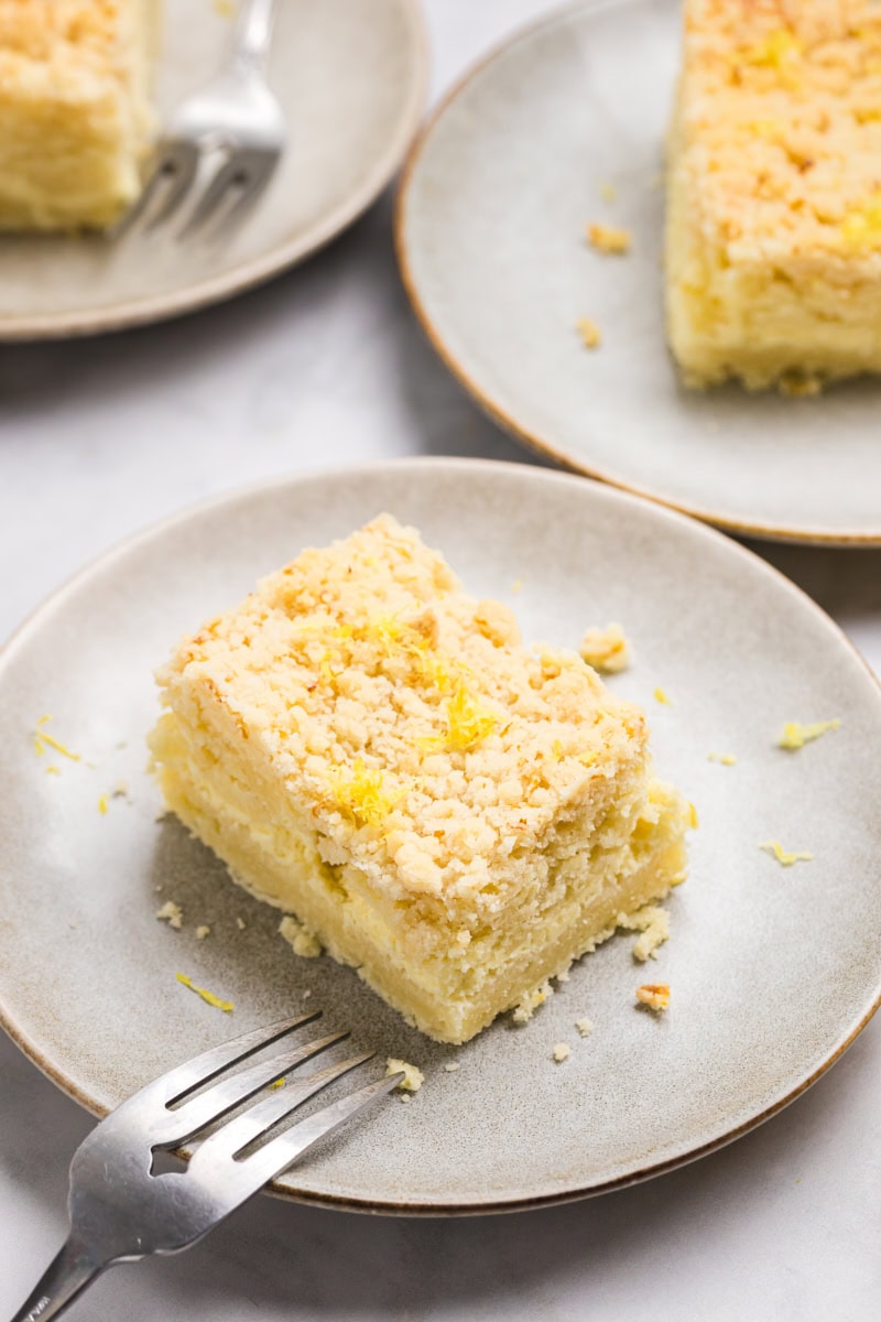 a slice of lemon cream cheese coffee cake on a plate with more servings in the background