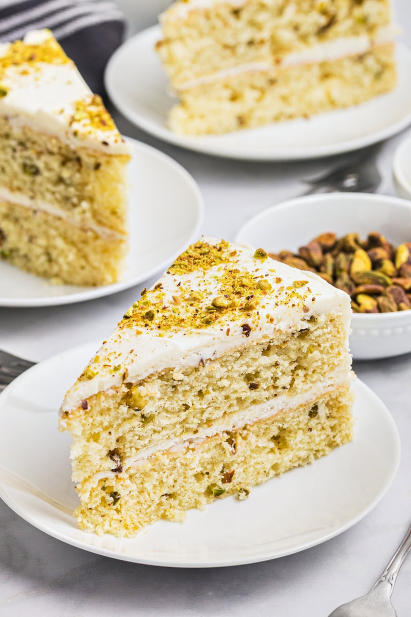 a slice of pistachio cake with white chocolate frosting