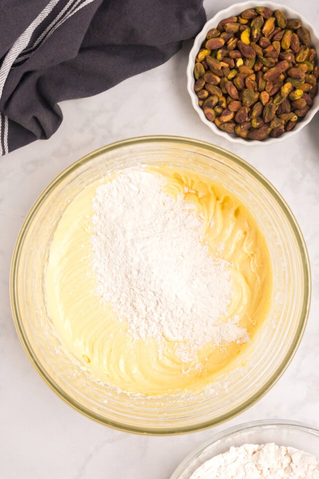 overhead view of dry ingredients added to wet ingredients for pistachio cake