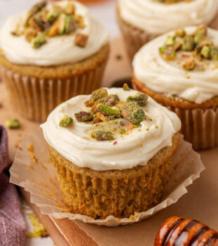 a pistachio cupcake with honey cream cheese frosting with the liner peeled away