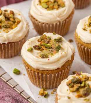 pistachio cupcakes topped with honey cream cheese frosting and garnished with chopped pistachios