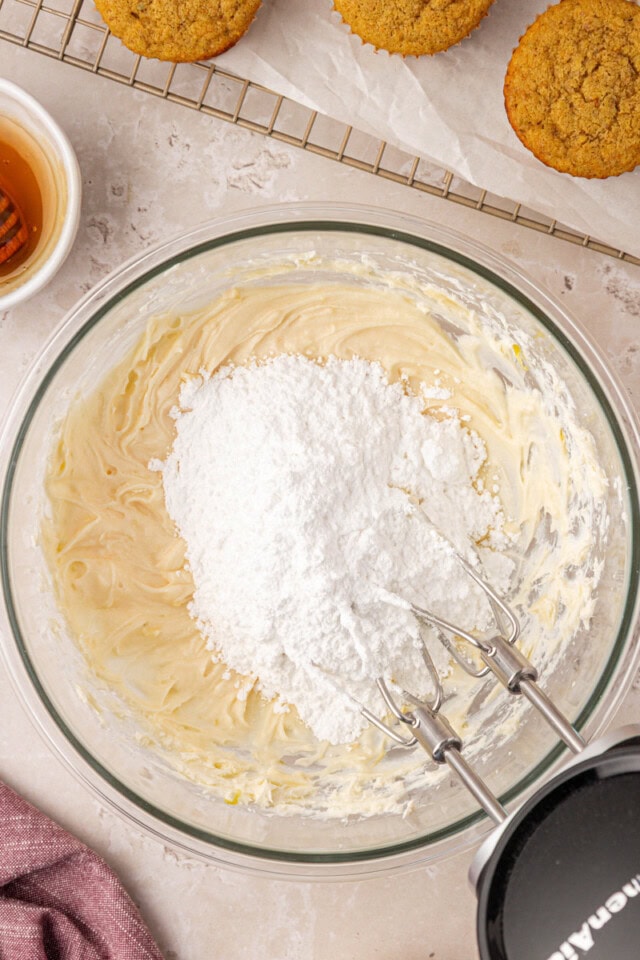 overhead view of confectioners' sugar added to beaten cream cheese