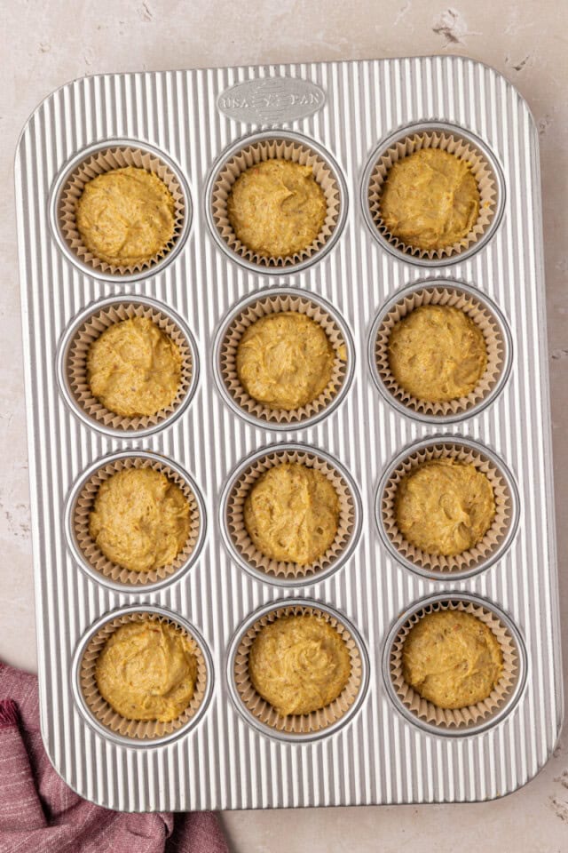 overhead view of pistachio cupcake batter in a muffin pan ready to go into the oven