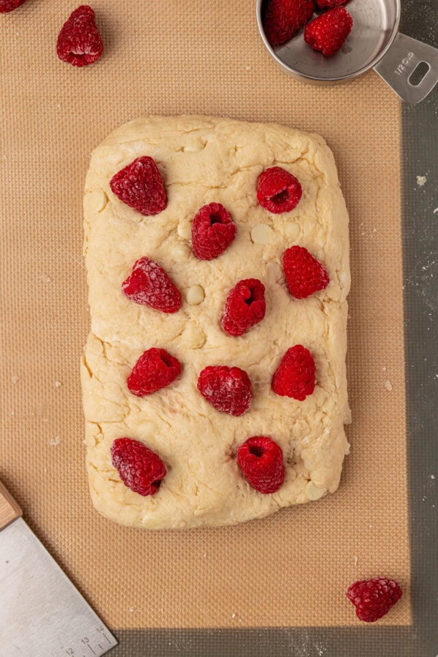 scone dough shaped into a rectangle and topped with raspberries