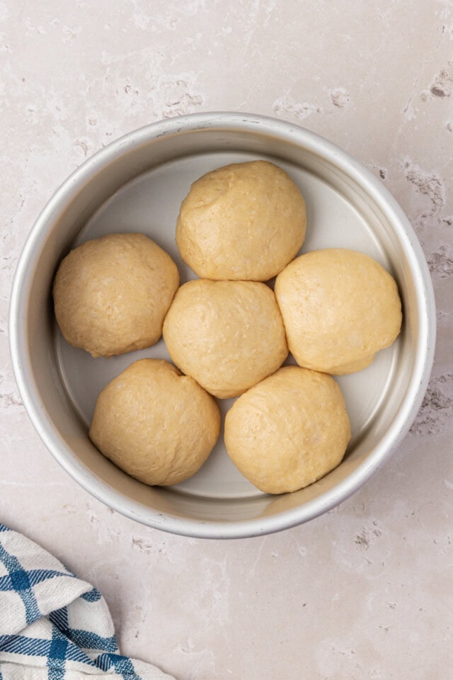 shaped dinner rolls in a round pan after rising