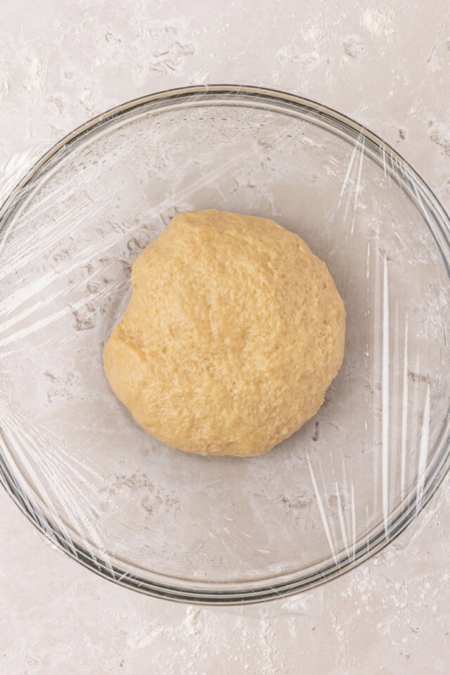 yeast bread dough in a bowl covered with plastic wrap