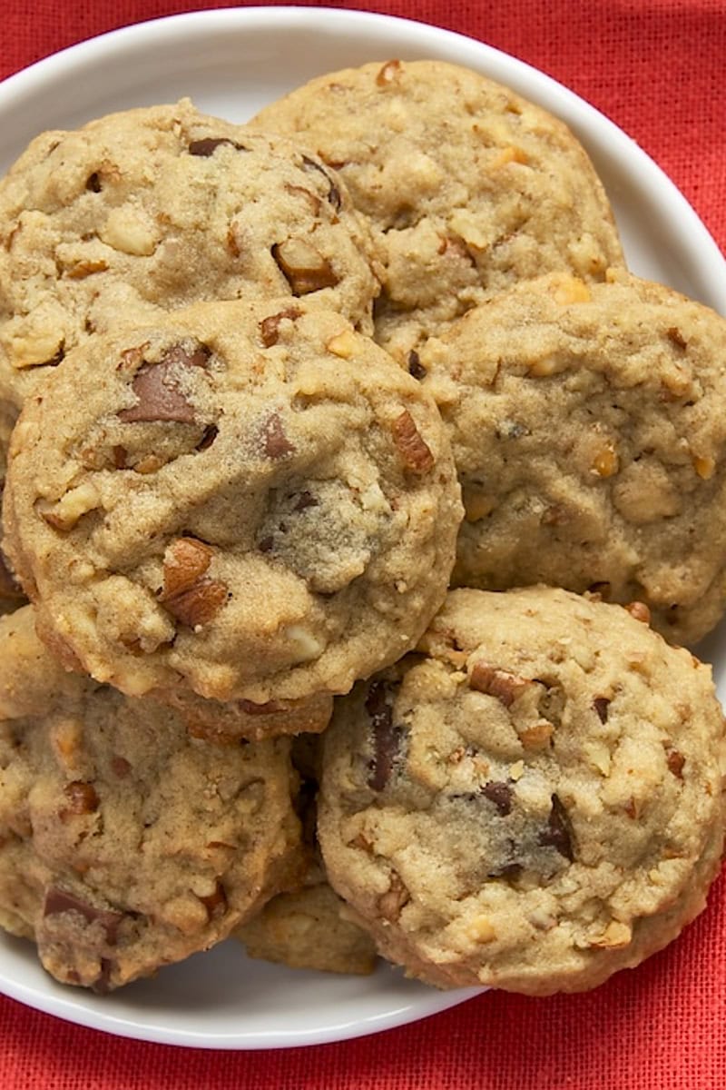 close up of nutty peanut butter cookies piled on a white plate