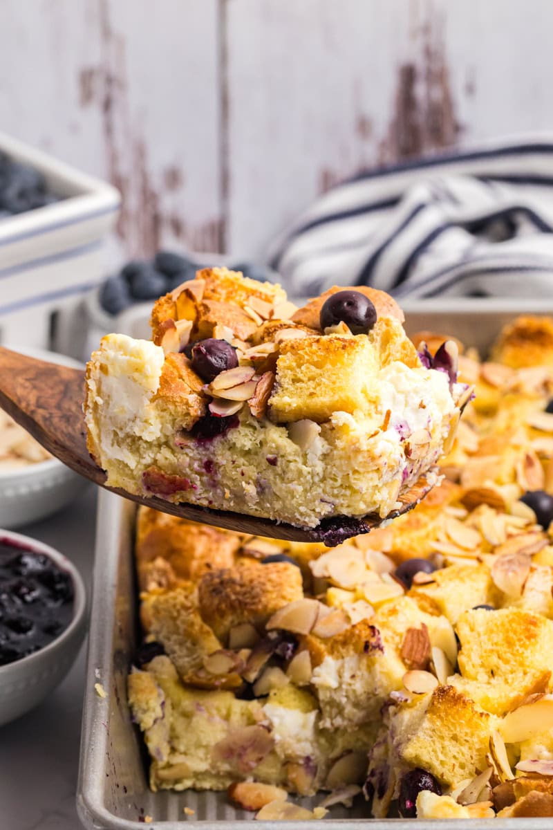 a slice of blueberry bread pudding being removed from the pan