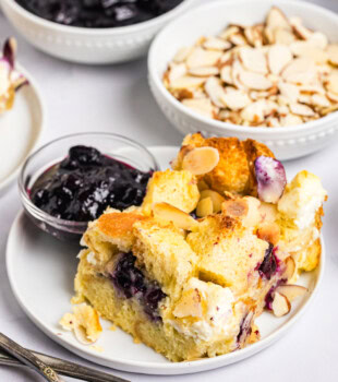 blueberry cream cheese bread pudding served on a plate with fresh blueberry sauce