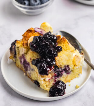 slice of baked blueberry bread pudding with golden top and soft center