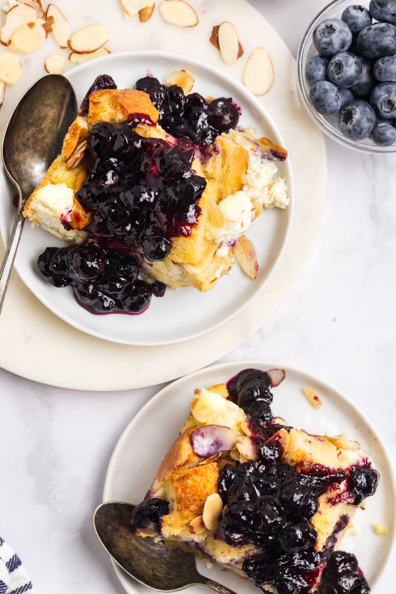 overhead view of two servings of blueberry bread pudding topped with fresh blueberry sauce