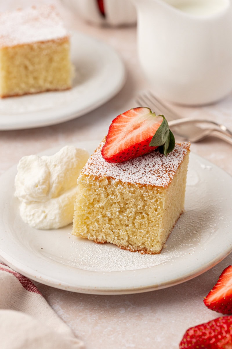 a slice of hot milk cake topped with powdered sugar and a strawberry slice