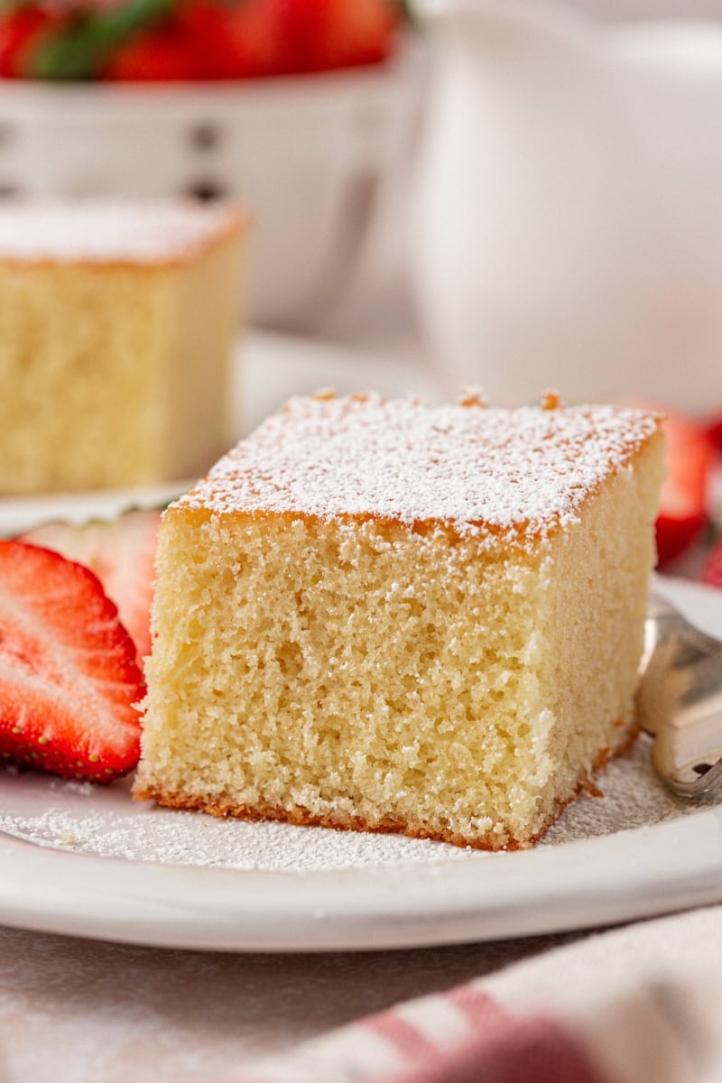 a slice of hot milk cake topped with powdered sugar and served with fresh strawberries