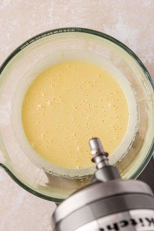 overhead view of beaten eggs and sugar in the bowl of a stand mixer