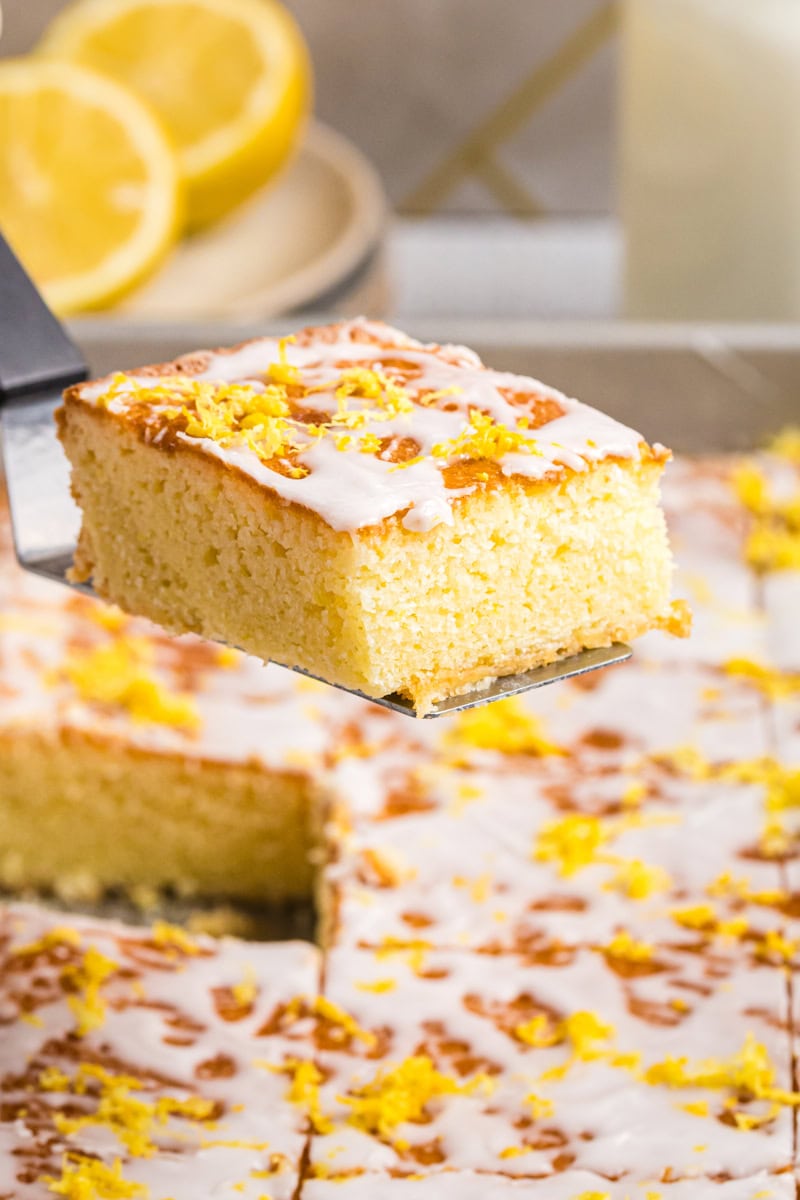 a lemon cake bar on a cake server being lifted from the pan