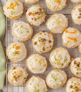 overhead view of Italian ricotta cookies topped with a glaze and garnished with chopped pistachios and citrus zest