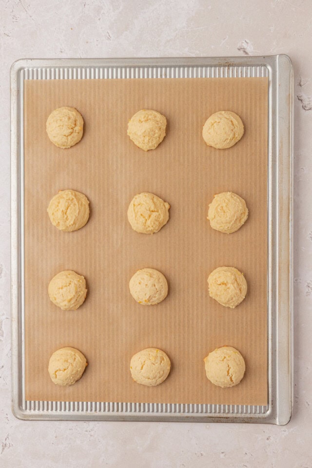 overhead view of freshly baked Italian ricotta cookies on a lined baking sheet