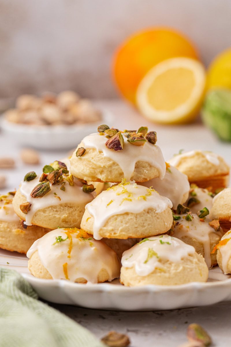 Italian ricotta cookies topped with a glaze and garnished with chopped pistachios and citrus zest