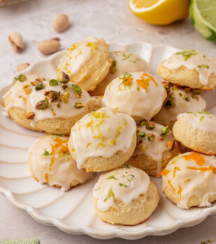 Italian ricotta cookies topped with a glaze and garnished with chopped pistachios and citrus zest