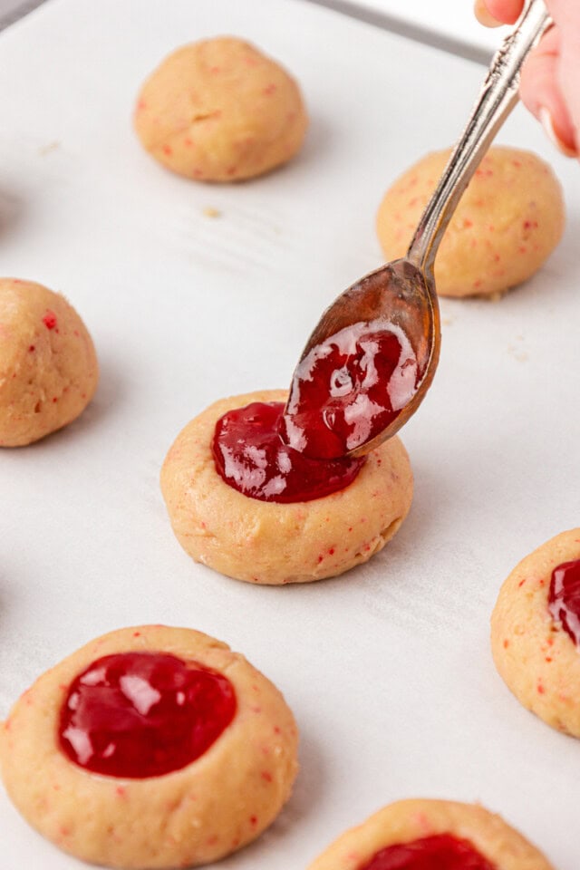thumbprint cookies being filled with strawberry jam before baking