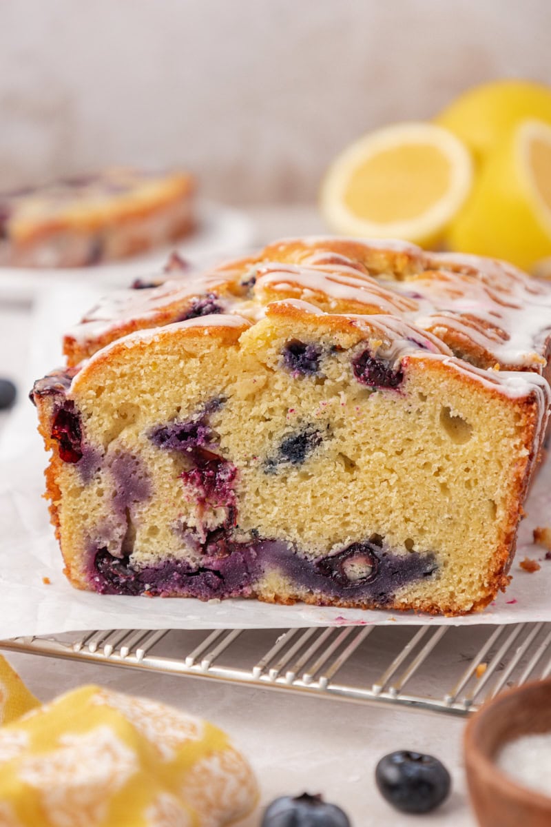 blueberry ricotta cake topped with lemon glaze, sliced to show soft texture and berries throughout the cake