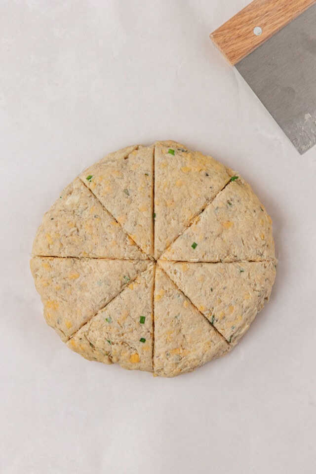overhead view of herb and cheese scone dough shaped into a circle and cut into wedges