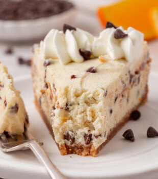 close up of a slice of chocolate chip-filled cannoli cheesecake with a bite missing