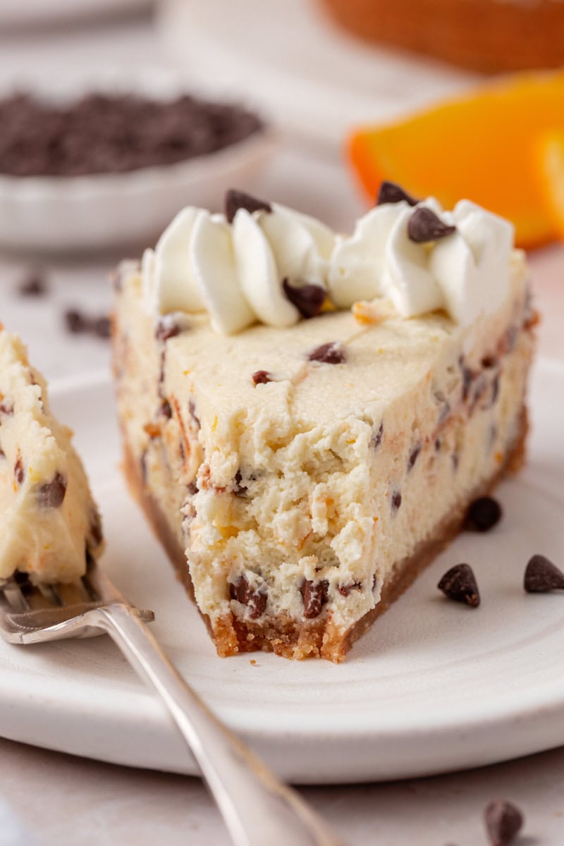 close up of a slice of chocolate chip-filled cannoli cheesecake with a bite missing
