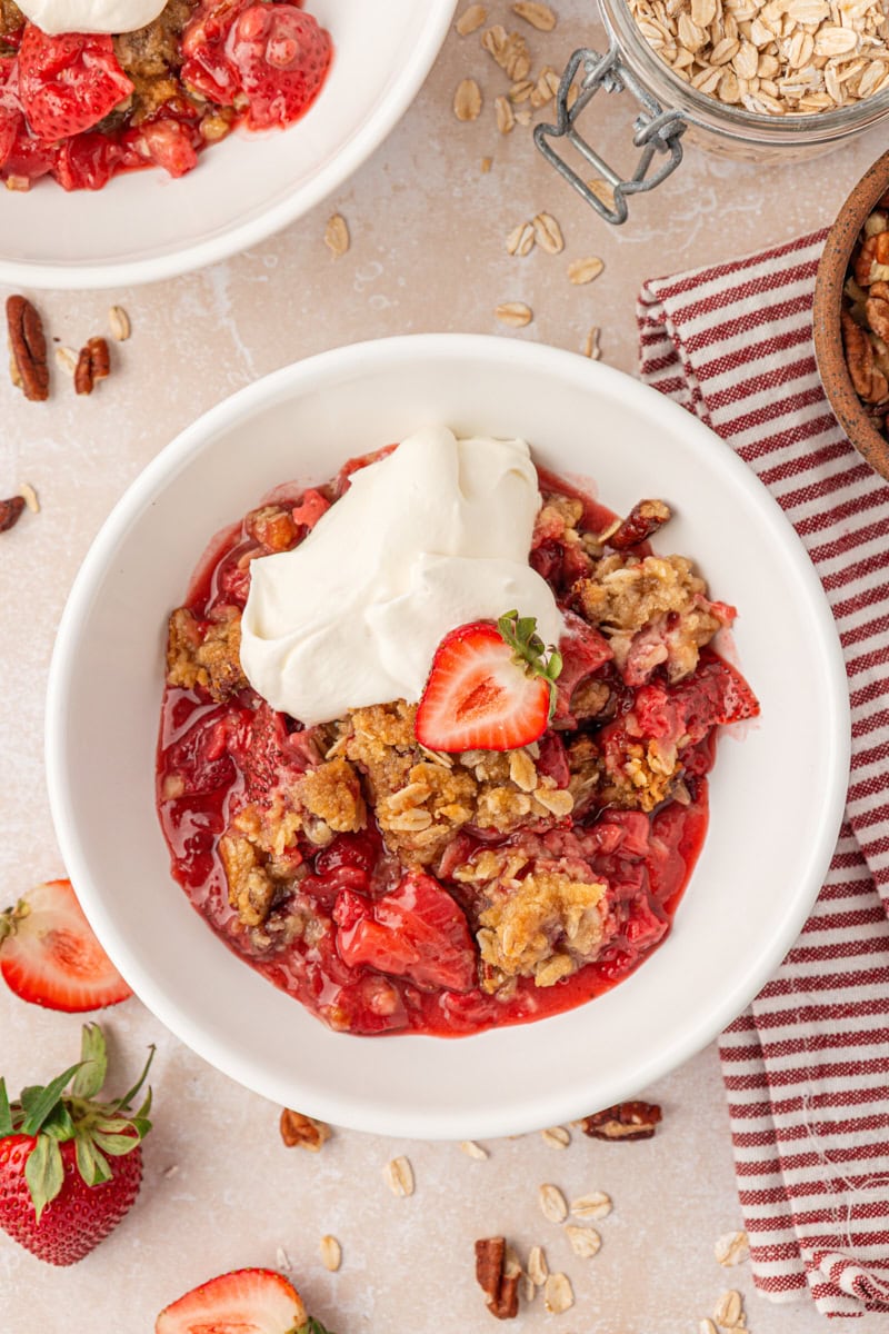 overhead view of a bowl of strawberry crisp topped with whipped cream