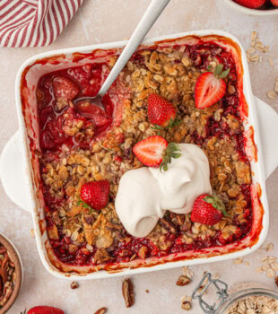 overhead view of fresh strawberry crisp with a buttery oat topping, served with whipped cream
