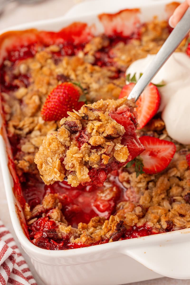 a spoonful of oat-topped strawberry crisp with remaining crisp in the background