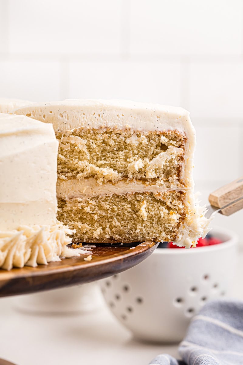 a slice of vanilla layer cake being removed from the remaining cake