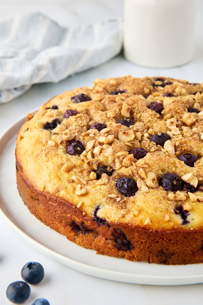 blueberry coffee cake with nutty cinnamon topping on a white cake plate