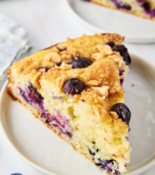 close up of a slice of soft, fluffy coffee cake filled with blueberries and topped with a nutty cinnamon topping