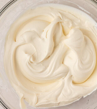closeup view of soft, creamy mascarpone whipped cream in a glass bowl