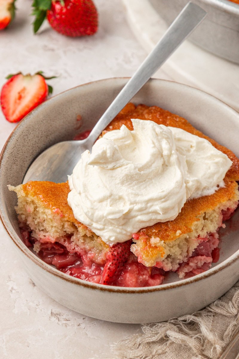 a big dollop of mascarpone whipped cream on a serving of a rustic strawberry cake