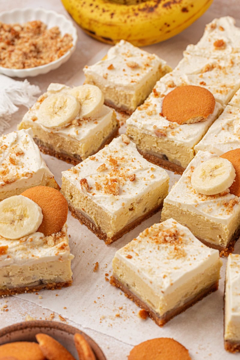 banana pudding cheesecake bars featuring layers of vanilla wafer crust, banana cheesecake filling, and whipped cream