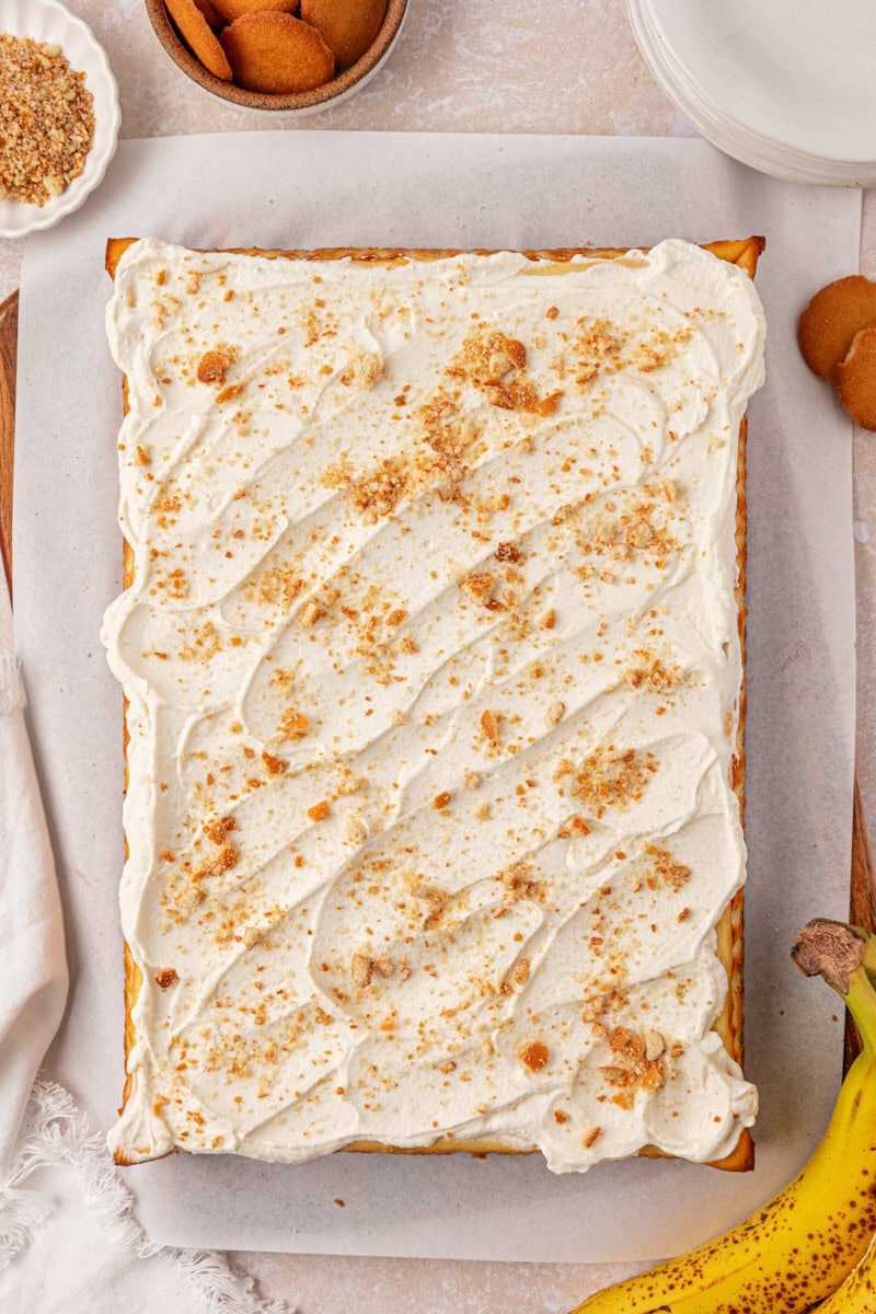 overhead view of banana pudding cheesecake bars topped with whipped cream and vanilla wafer crumbs