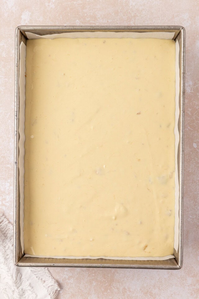 banana cheesecake filling poured over bananas and crust in a baking pan