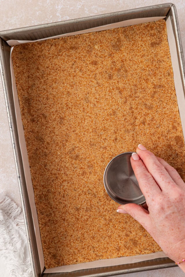 vanilla wafer crust mixture being pressed into a baking pan