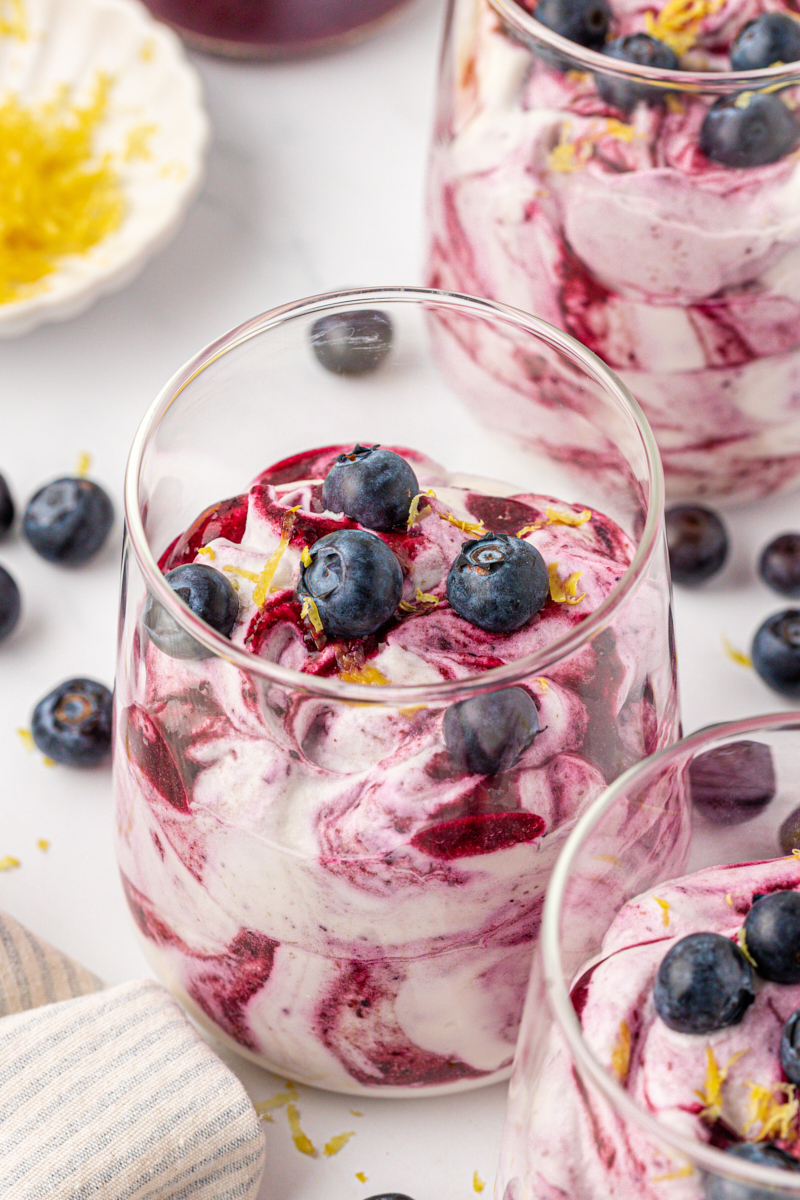 blueberry fool made with blueberry puree swirled into whipped cream, served in glasses and topped with fresh blueberries and lemon zest