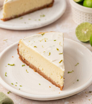 slice of Key lime cheesecake with graham cracker crust and sour cream topping