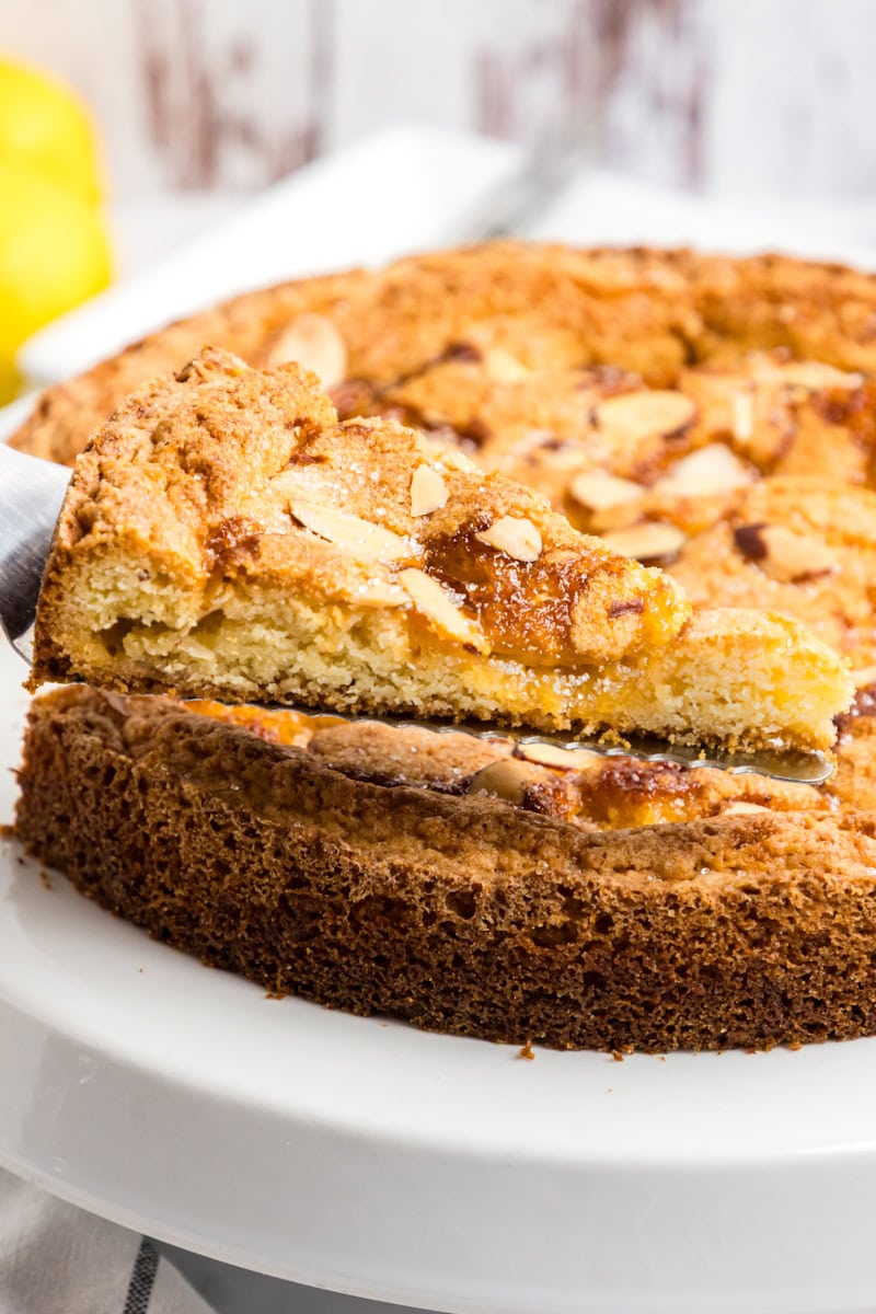 a slice of lemon almond butter cake on a cake server with remaining cake in the background