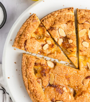 overhead view of partially sliced lemon almond cake with pockets of lemon curd and sliced almonds on top
